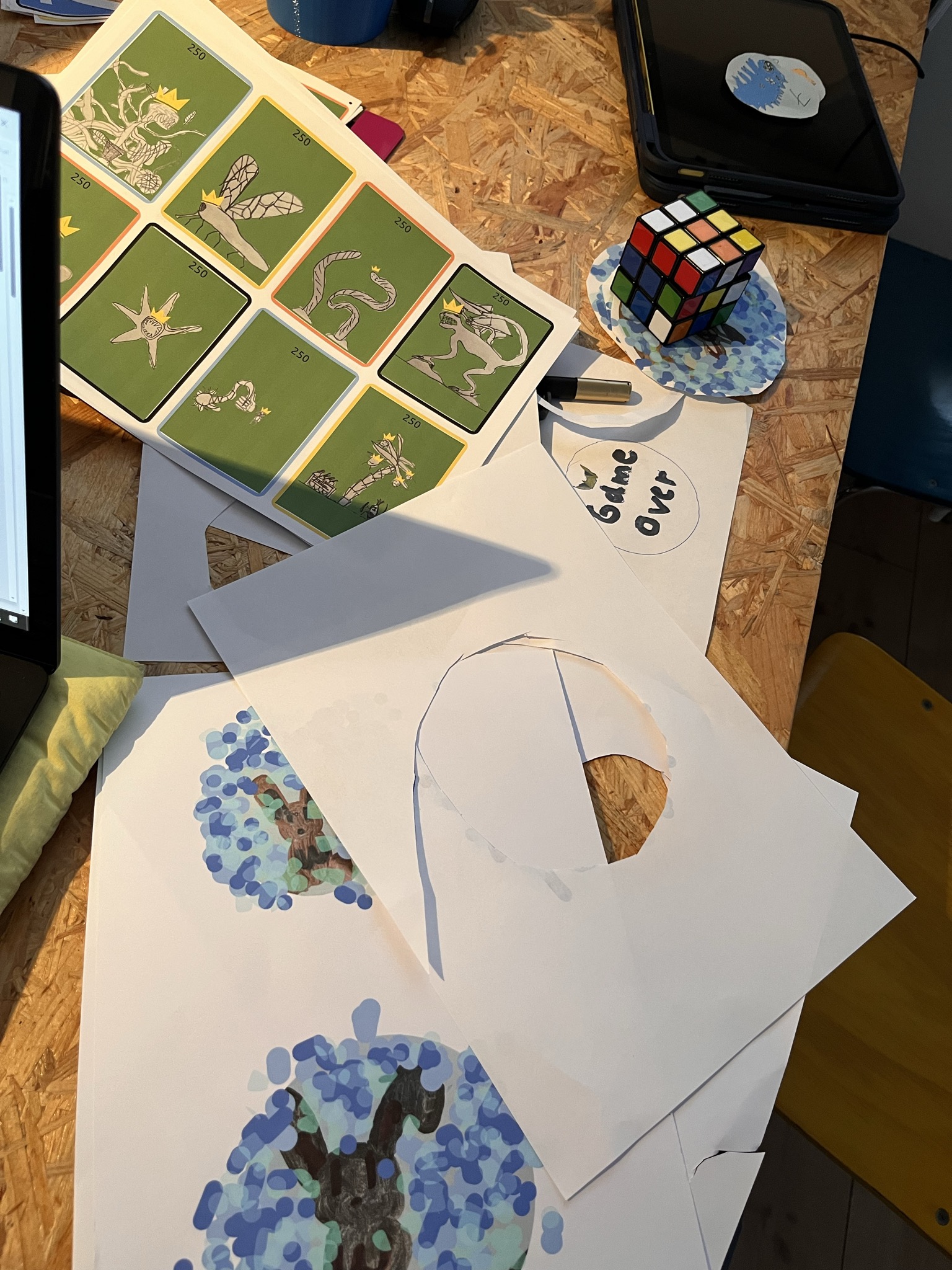 Selbst entworfene Spielkarten und Illustrationen auf dem Tisch mit Rubik’s Cube